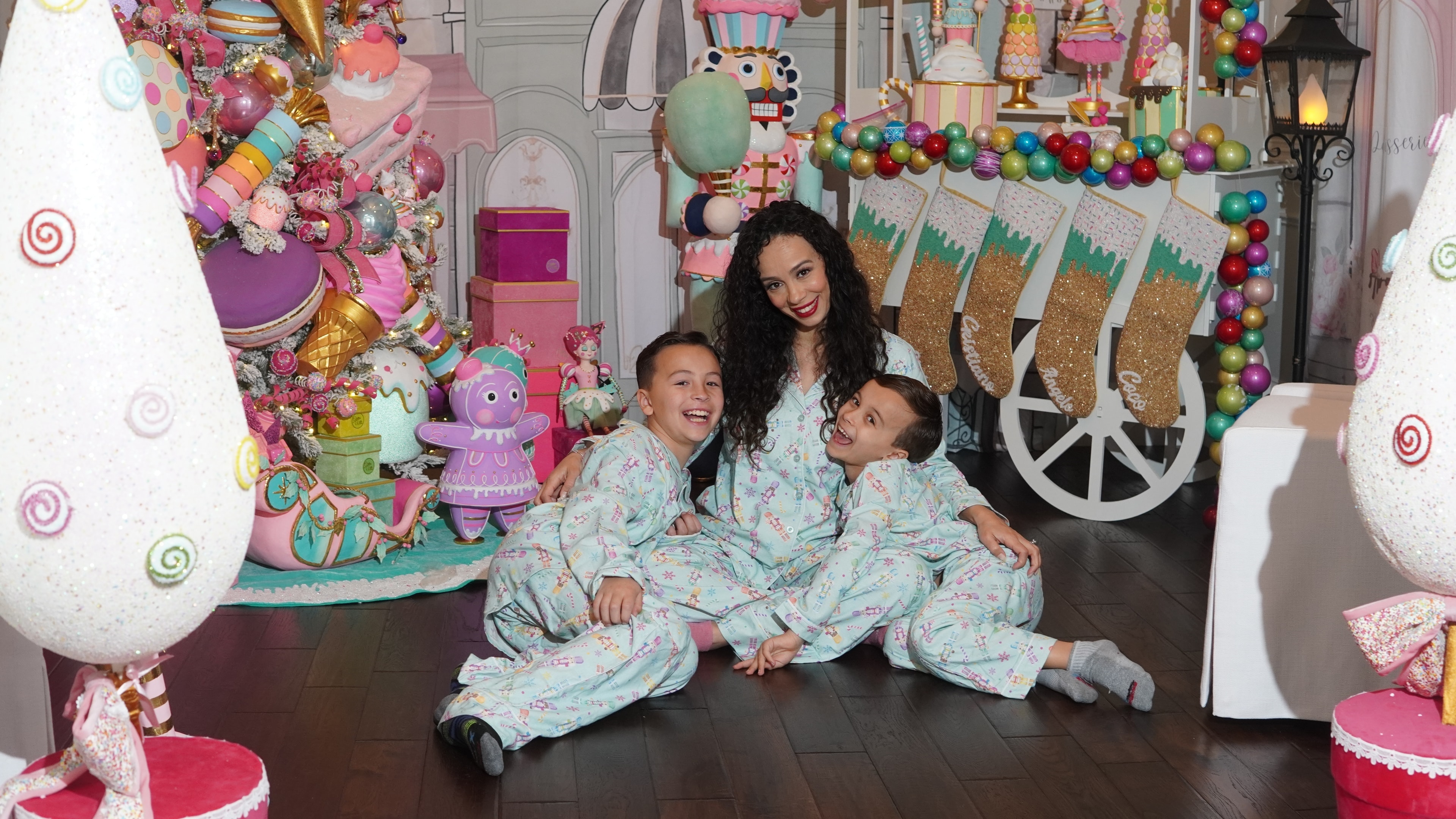 Lisa Marie laughing with her boys in front of a candy-themed holiday installation